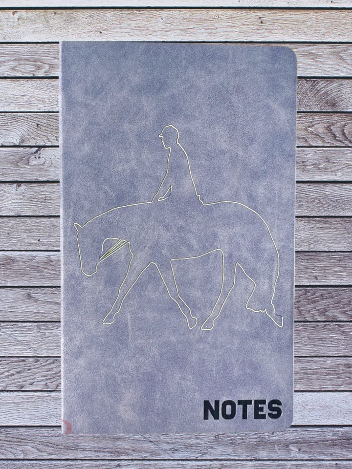 Front cover of blue note book with engraved hunt seat rider design 